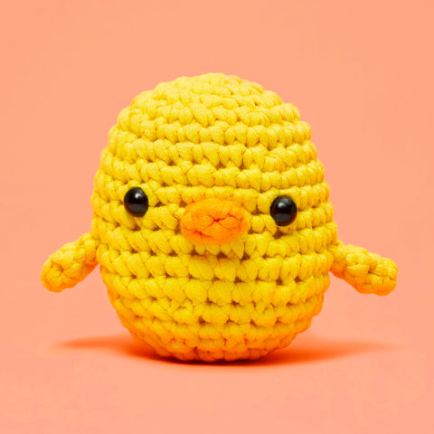 Yellow crochet duck toy on a pink background